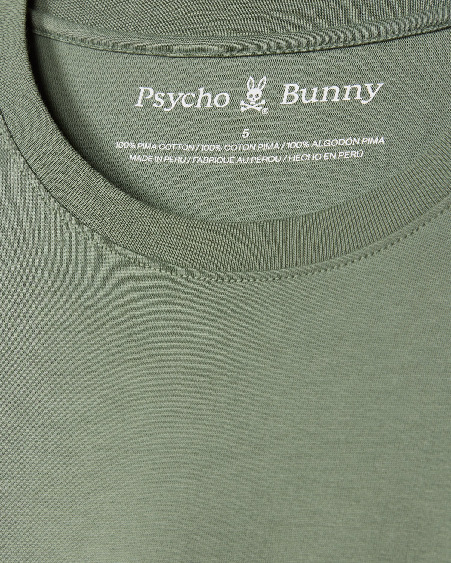Close-up of the MENS ALBERTON LONG SLEEVE TEE - B6T867D200 in vibrant green, prominently displaying the Psycho Bunny label along with a small bunny logo. The label details the size and confirms that it is made from 100% Pima cotton, crafted in Peru—a true fashion masterpiece.