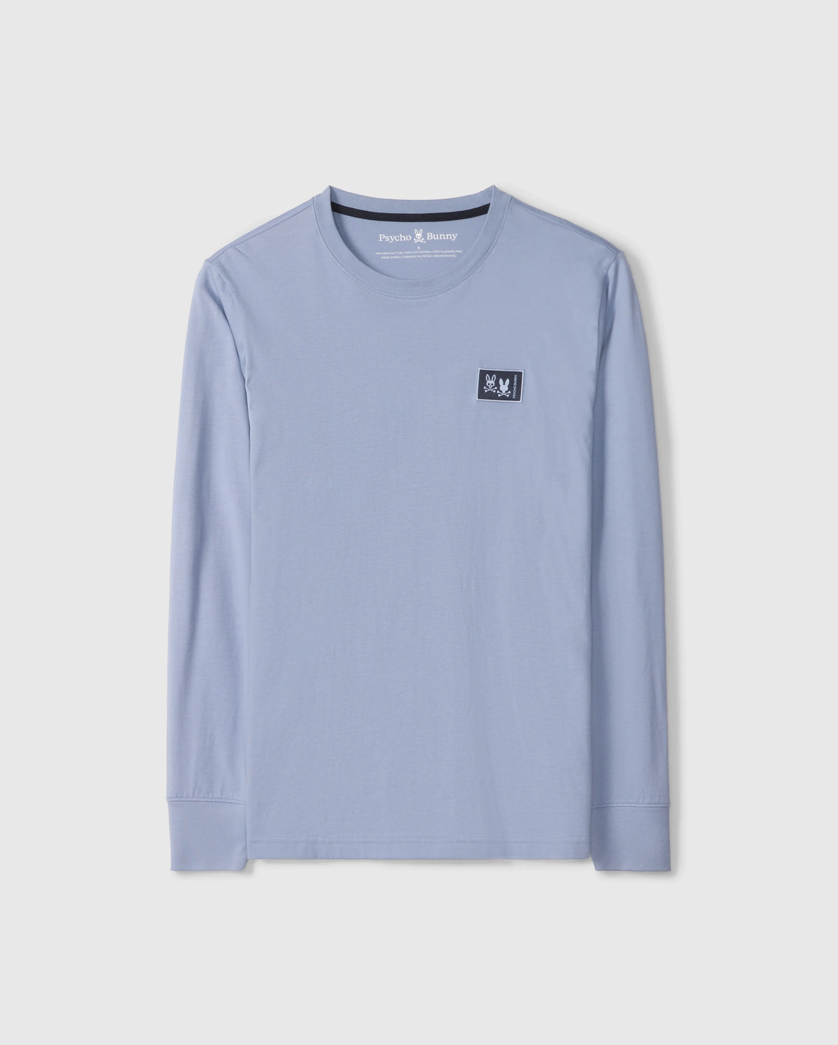 The Psycho Bunny MENS MONROE LONG SLEEVE TEE - B6T975D200, in light blue, is a comfortable long-sleeve t-shirt made from pima cotton. It features a round neckline and a small black patch with a white design on the upper chest for added versatile style.