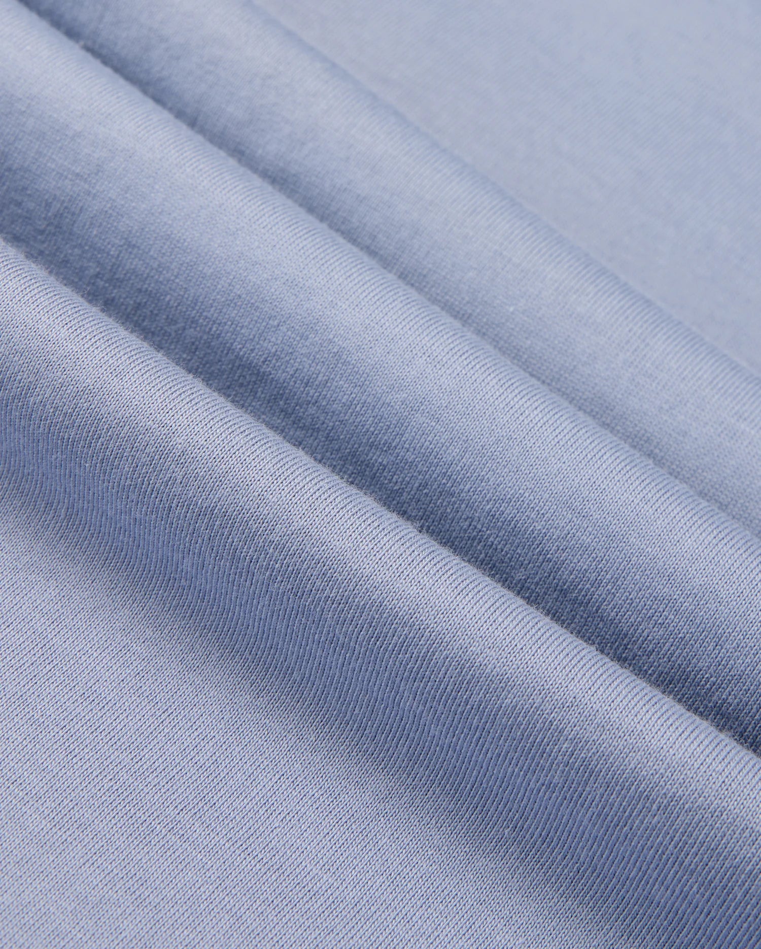 Close-up of folded light blue fabric from the Psycho Bunny MENS MONROE LONG SLEEVE TEE - B6T975D200, highlighting its smooth texture and fine weave. Crafted from pima cotton, it embodies classic comfort.