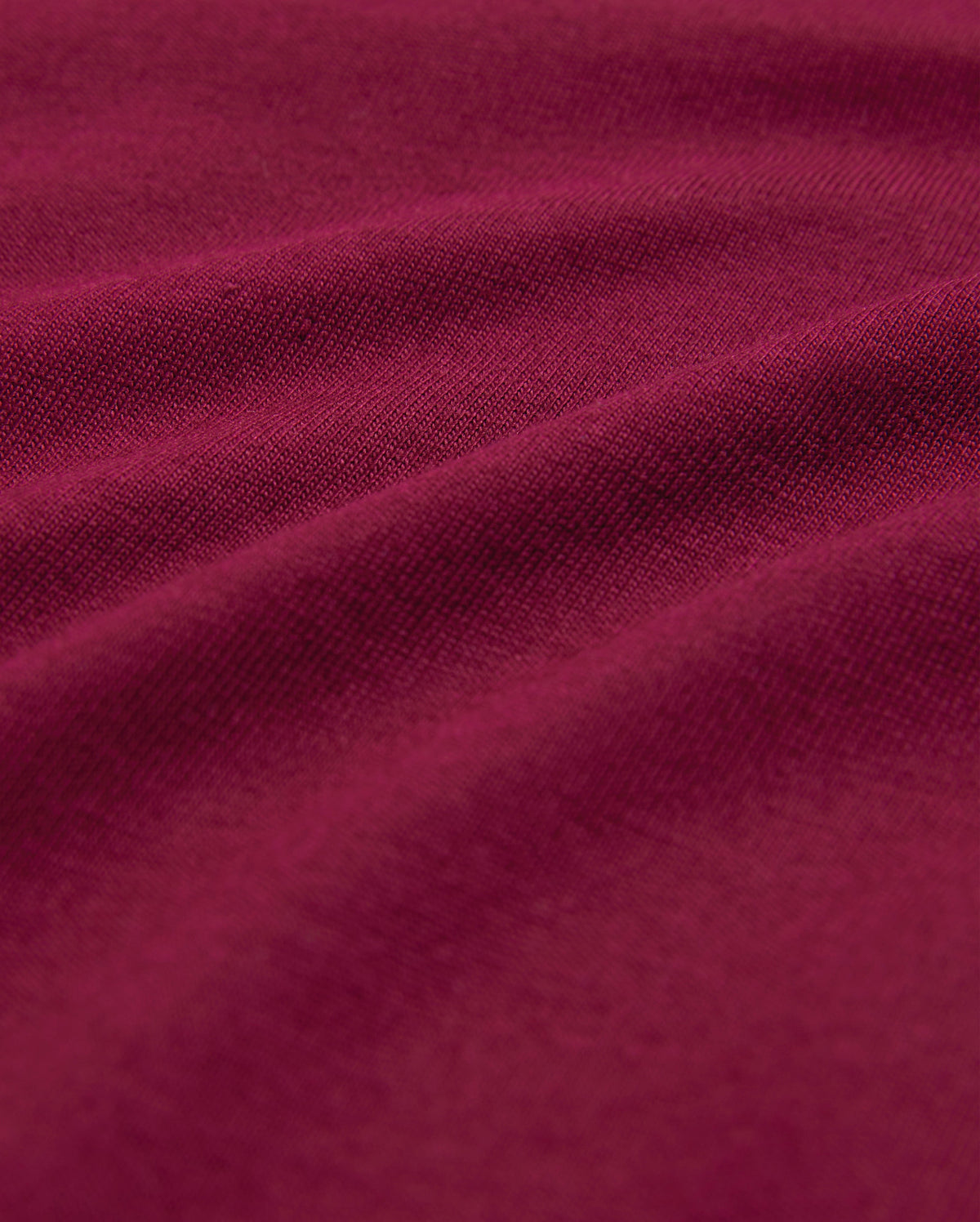 Close-up image of a rich, burgundy-colored fabric with visible texture and gentle folds, highlighting its soft and smooth surface—perfect for a breathable and lightweight men's crewneck tee made from luxurious Pima cotton: the MENS CLASSIC CREW NECK TEE - B6U014Z1PC by Psycho Bunny.