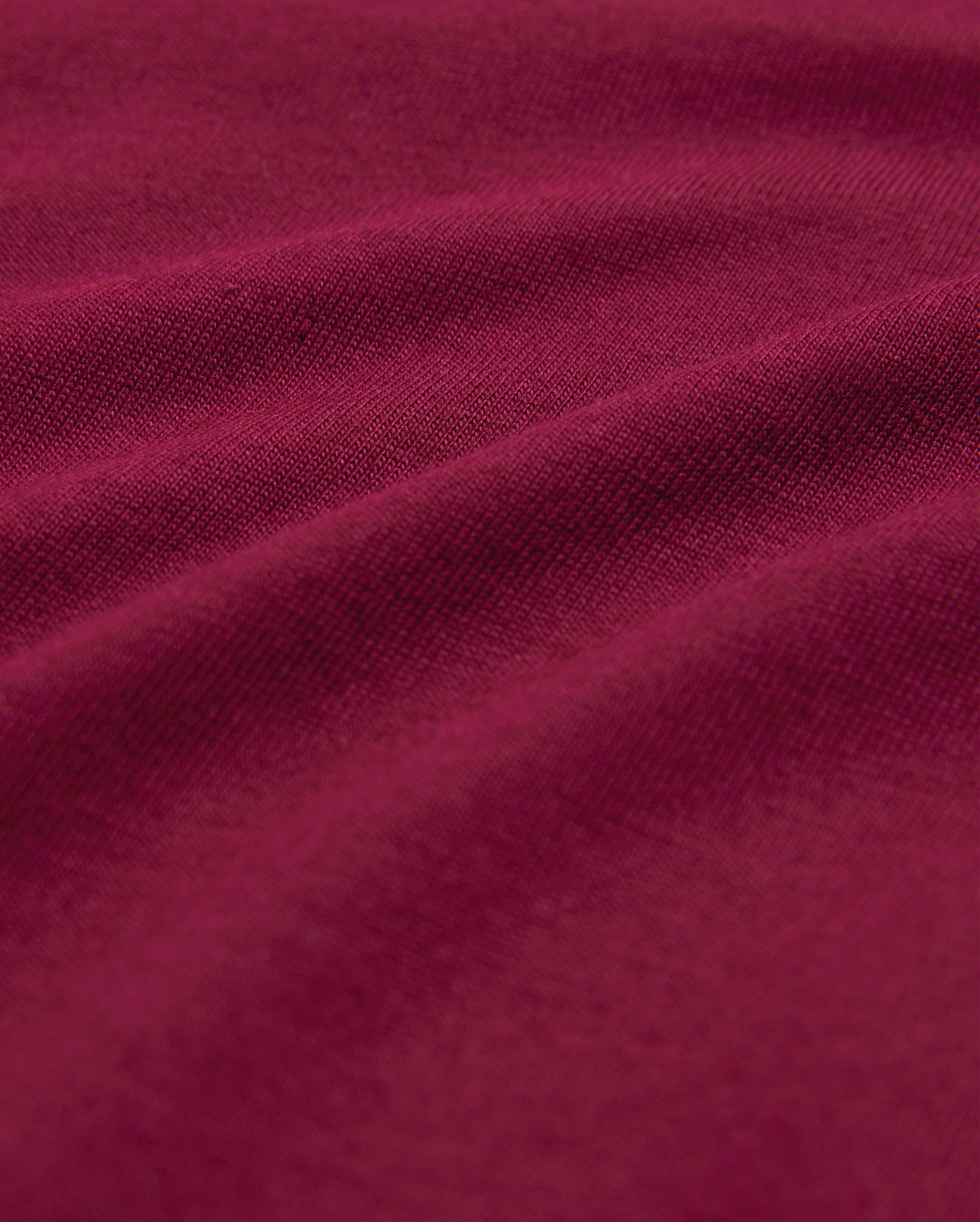 Close-up image of a rich, burgundy-colored fabric with visible texture and gentle folds, highlighting its soft and smooth surface—perfect for a breathable and lightweight men's crewneck tee made from luxurious Pima cotton: the MENS CLASSIC CREW NECK TEE - B6U014Z1PC by Psycho Bunny.