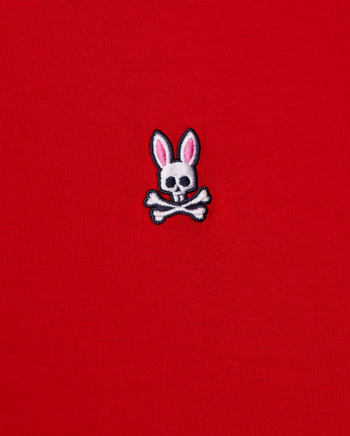 The MENS CLASSIC V NECK TEE - B6U100CRPC from Psycho Bunny showcases a red fabric made of soft Pima cotton and features the brand's signature logo: a white skull and crossbones with playful pink bunny ears.