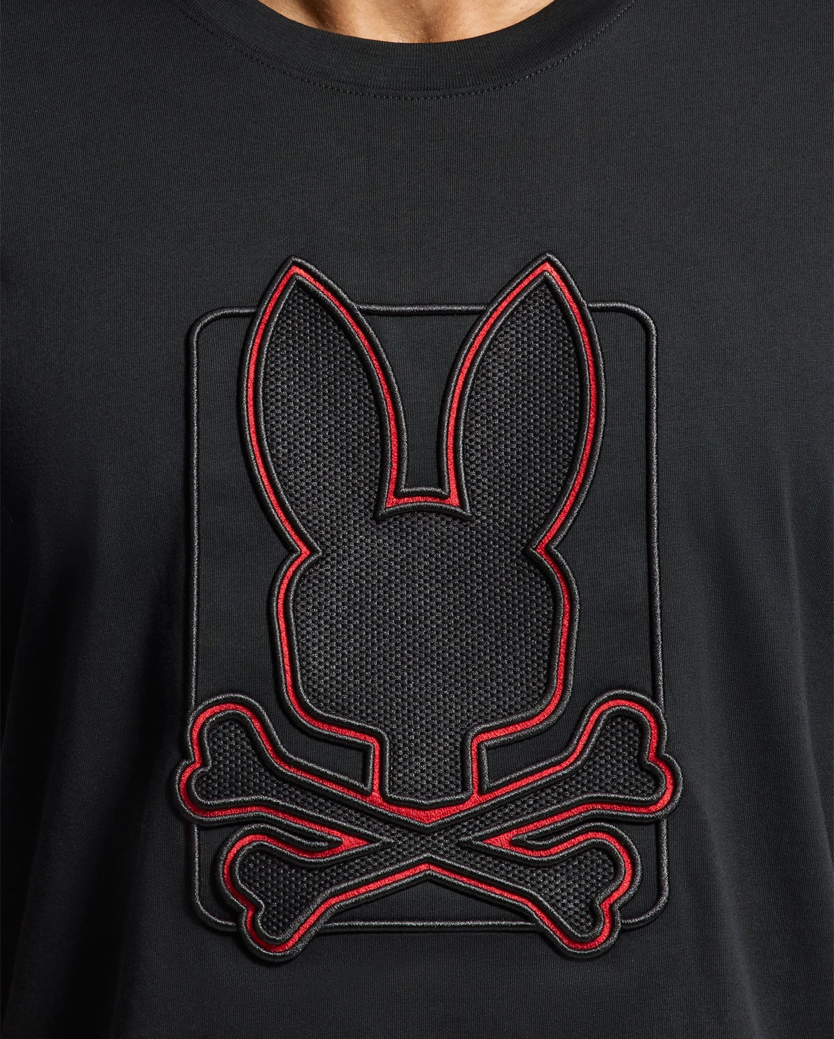 The Psycho Bunny MENS PIERCE EMBROIDERED GRAPHIC TEE - B6U115E200 features a distinctive bunny silhouette above crossed bones, outlined in red, crafted from durable black Pima cotton.