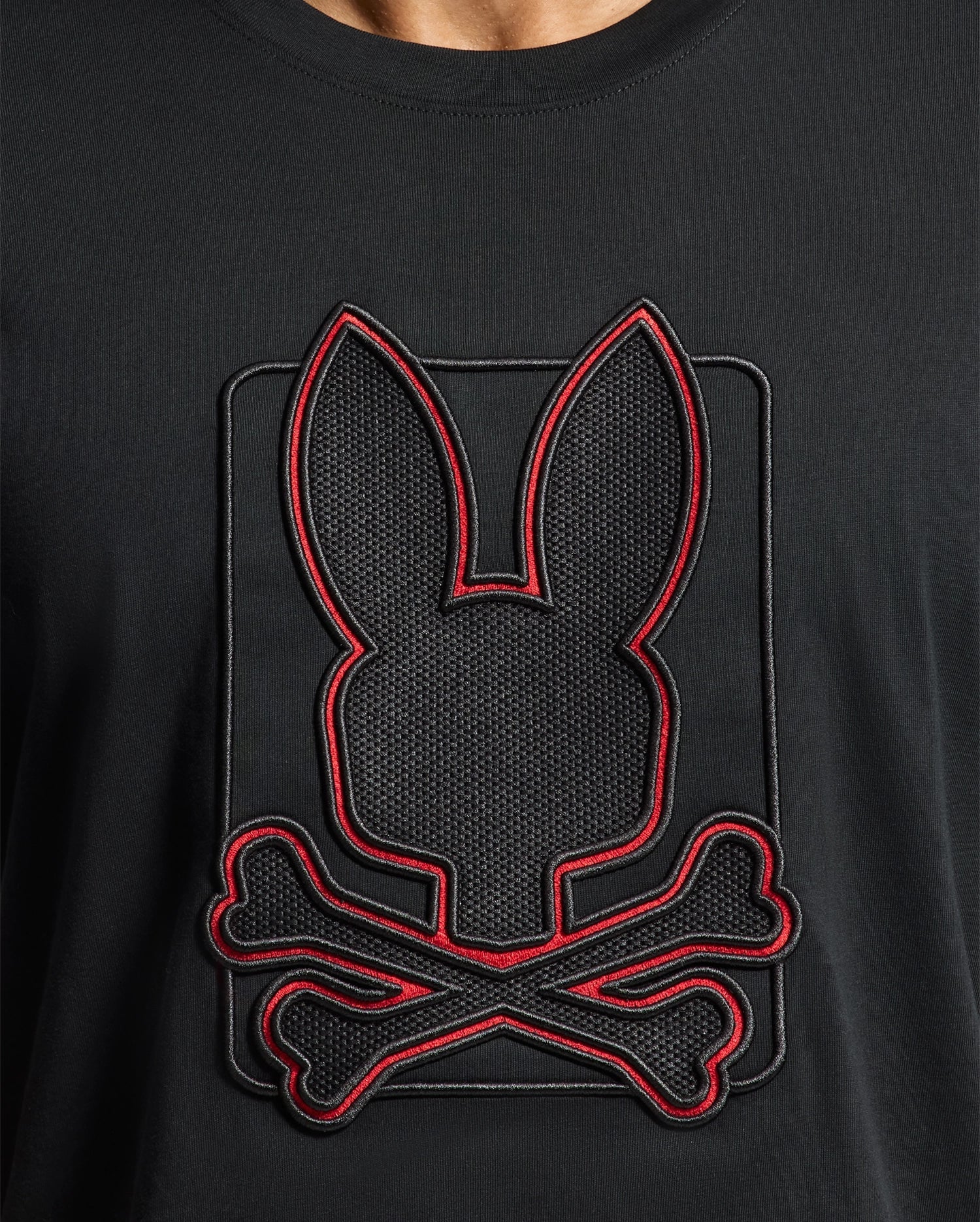 The Psycho Bunny MENS PIERCE EMBROIDERED GRAPHIC TEE - B6U115E200 features a distinctive bunny silhouette above crossed bones, outlined in red, crafted from durable black Pima cotton.