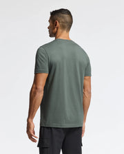The man wearing the Men's Pierce Embroidered Graphic Tee (B6U115E200) by Psycho Bunny and black cargo shorts is turned away from the camera against a white background, subtly highlighting the unique bunny embroidery that enhances the design.