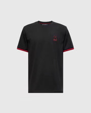 The Psycho Bunny MENS PIERCE FASHION TEE - B6U140E200 is crafted from Pima cotton and showcases red accents on the sleeve edges along with an embroidered Bunny patch emblem on the chest, set against a plain gray background.