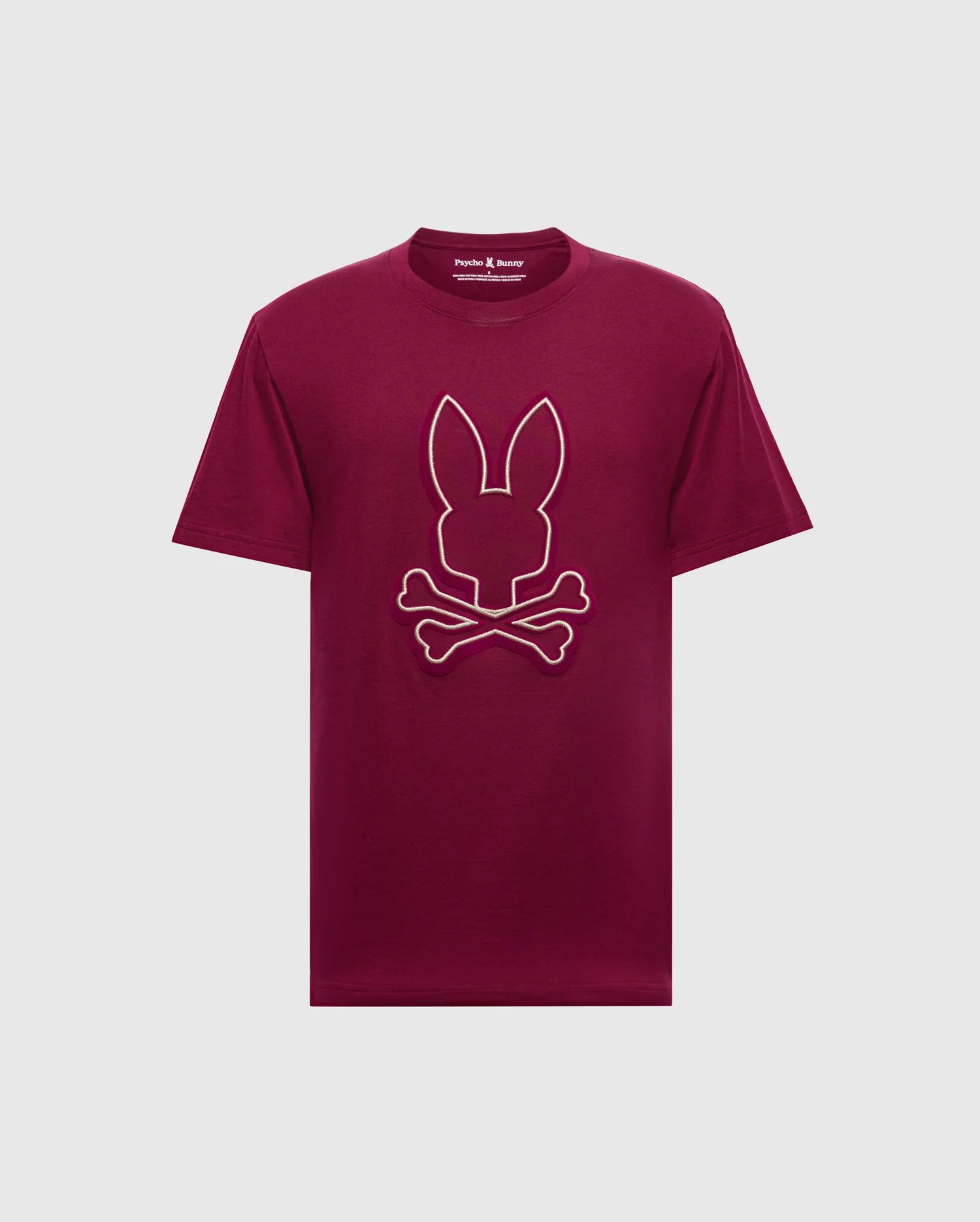 The Psycho Bunny MENS ALEXANDER GRAPHIC TEE - B6U163E200 is a striking maroon men's graphic t-shirt made from soft Pima cotton, featuring a bold graphic of a bunny head above crossed bones against a plain light gray backdrop.