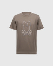 The Men's Alexander Graphic Tee - B6U163E200 by Psycho Bunny features a bold brown color with a distinctive white outline of rabbit ears above crossed bones, reminiscent of the classic skull and crossbones motif. Crafted from soft Pima cotton, it ensures both comfort and style in one unique package.