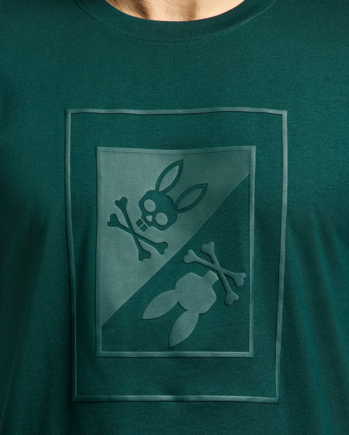 This MENS DOTSERO GRAPHIC TEE - B6U197E200 by Psycho Bunny is crafted from luxurious Peruvian Pima Cotton and showcases a unique green color. Its graphic design features a stylized skull and crossbones on one side and bunny ears with crossbones on the other, creating a striking mirrored effect with a diagonal division.