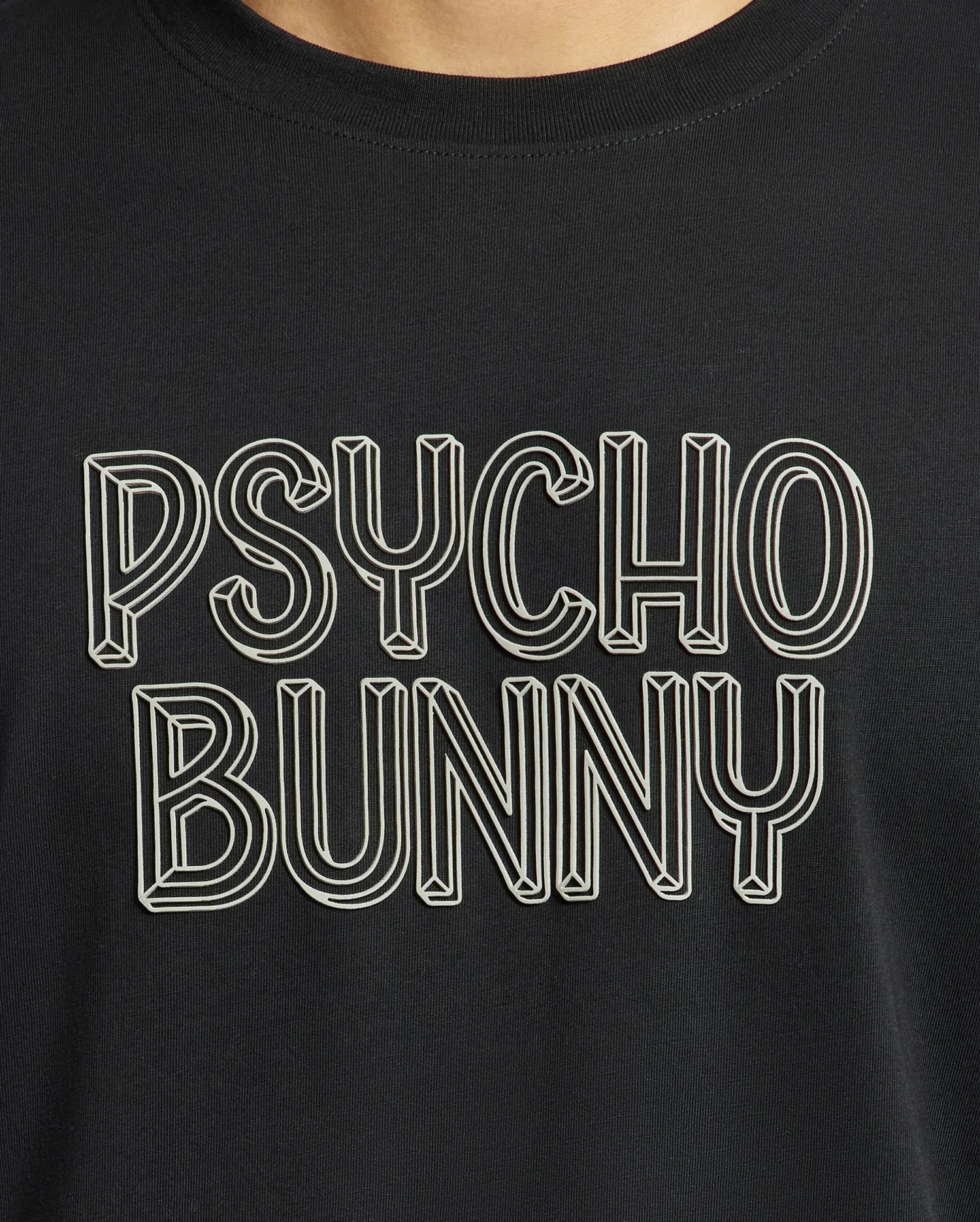 A close-up of the Mens Monarc Wordmark Graphic Tee - B6U210E200 from Psycho Bunny showcases bold white outlined text reading "PSYCHO BUNNY" in a stylized, three-dimensional font against a black backdrop. Made from 100% Pima cotton, it provides a regular fit that ensures ultimate comfort and style.