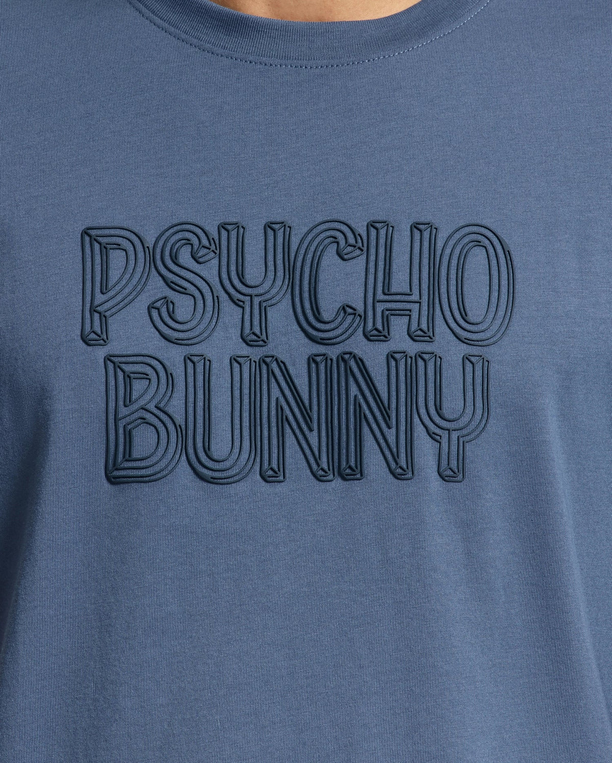 Close-up of the men's Monarc Wordmark Graphic Tee by Psycho Bunny, crafted in premium Pima cotton, featuring embossed text that reads "PSYCHO BUNNY," offering unparalleled comfort.