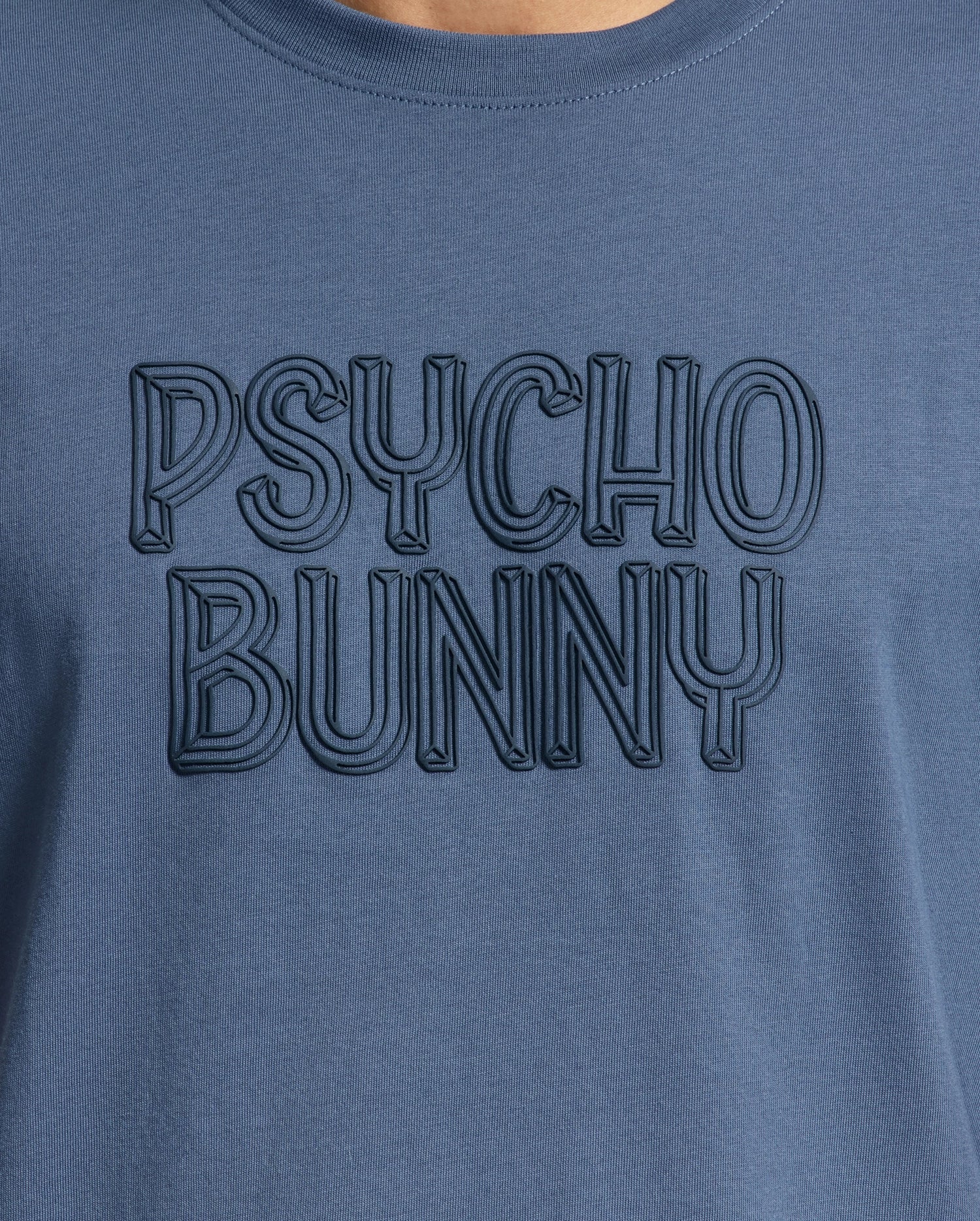 Close-up of the men's Monarc Wordmark Graphic Tee by Psycho Bunny, crafted in premium Pima cotton, featuring embossed text that reads "PSYCHO BUNNY," offering unparalleled comfort.