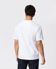 A person with short dark hair is standing and facing away from the camera. They are wearing a plain white Psycho Bunny MENS OVERSIZED CLASSIC CREW NECK TEE - B6U240W1PC made from pima cotton and dark blue jeans, against a plain, light-colored background.