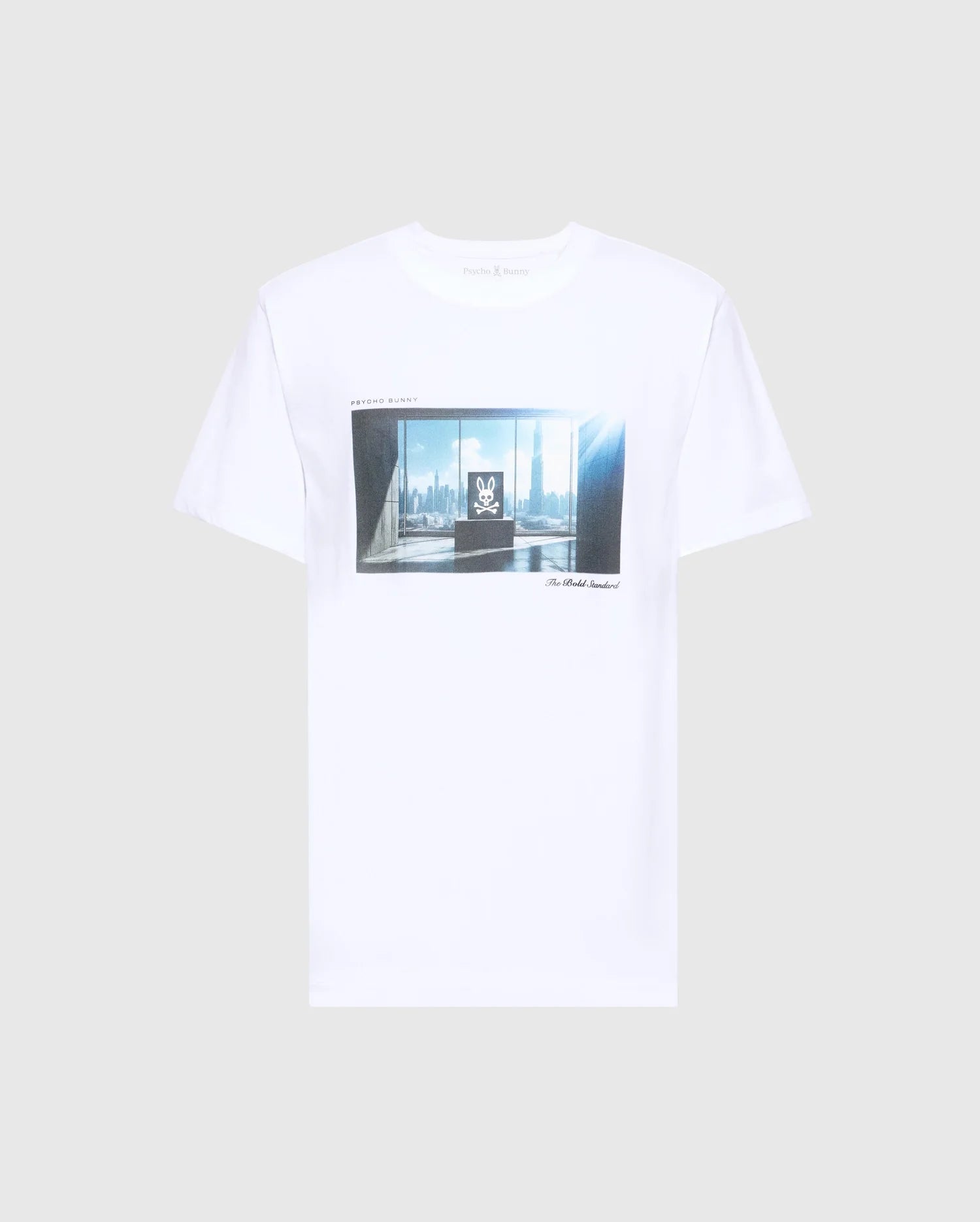The MENS WARREN PHOTO REAL TEE - B6U388E200 by Psycho Bunny is a white Pima cotton jersey shirt showcasing a city skyline through large windows, with abstract elements and text graphics. Set against a gray background, this tee offers style and comfort for urban enthusiasts.