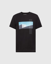 The Psycho Bunny MENS NEIL PHOTO REAL TEE (B6U389E200) is a black jersey Pima cotton t-shirt showcasing a sky view silhouette graphic with vertical text, combining comfort with modern style.