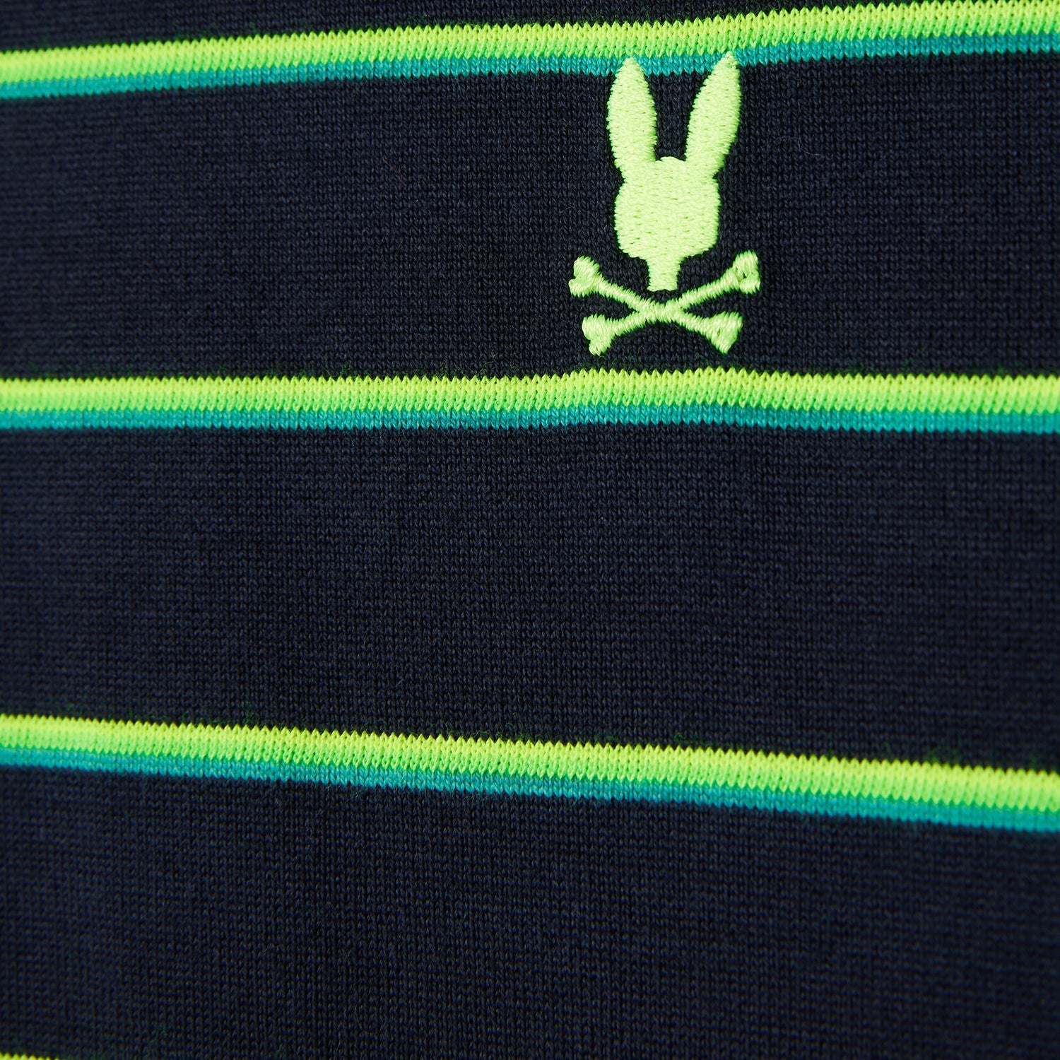 Close-up of a dark blue heavyweight jersey knitted fabric with horizontal green and teal stripes, featuring a neon green embroidered emblem of a rabbit skull and crossbones in between the 90s-inspired two-tone stripes. This is the MENS ALTON STRIPE OVERSIZED TEE - B6U409C200 from Psycho Bunny.
