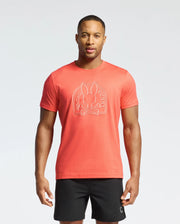 A man stands against a white background wearing Psycho Bunny's MENS MELBOURNE GRAPHIC TEE in red, crafted from soft, eco-friendly Peruvian Pima Cotton, featuring a charming bunny design and paired with black shorts.