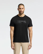 A man with a buzz cut wears a black MENS BERNI EMBROIDERED WORDMARK GRAPHIC TEE from Psycho Bunny, crafted from plush Pima cotton. "Psycho Bunny" is embroidered on the logo. He pairs it with beige pants and stands against a plain white background.