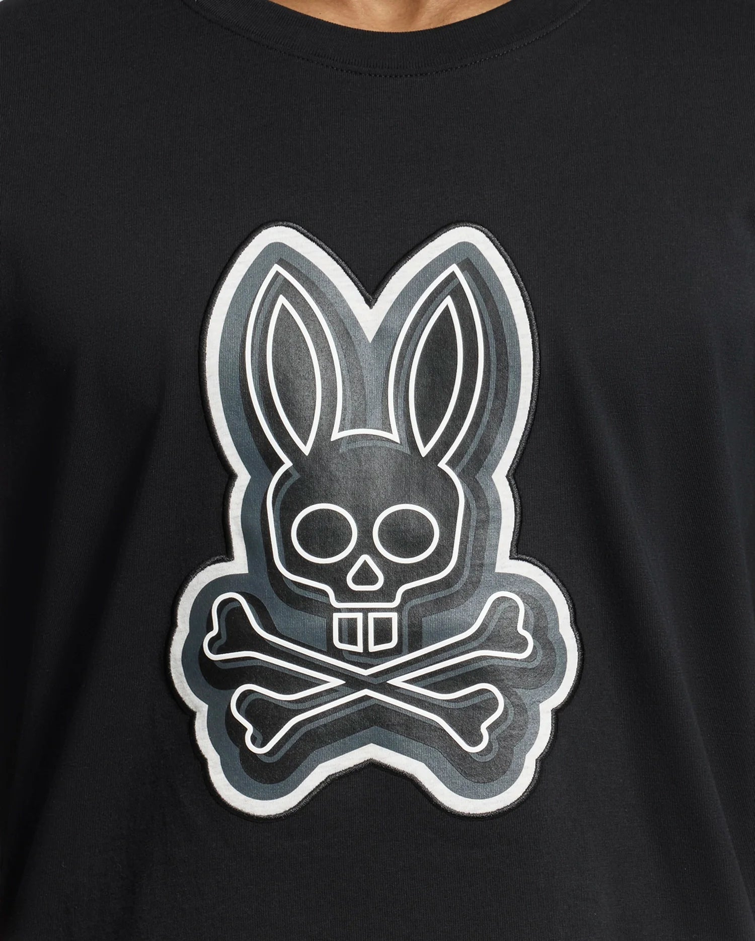 The Psycho Bunny MENS SYDNEY GRAPHIC TEE - B6U508F200 is a black Pima cotton shirt with a bold cartoonish rabbit skull and crossbones graphic in white, creating a striking contrast.