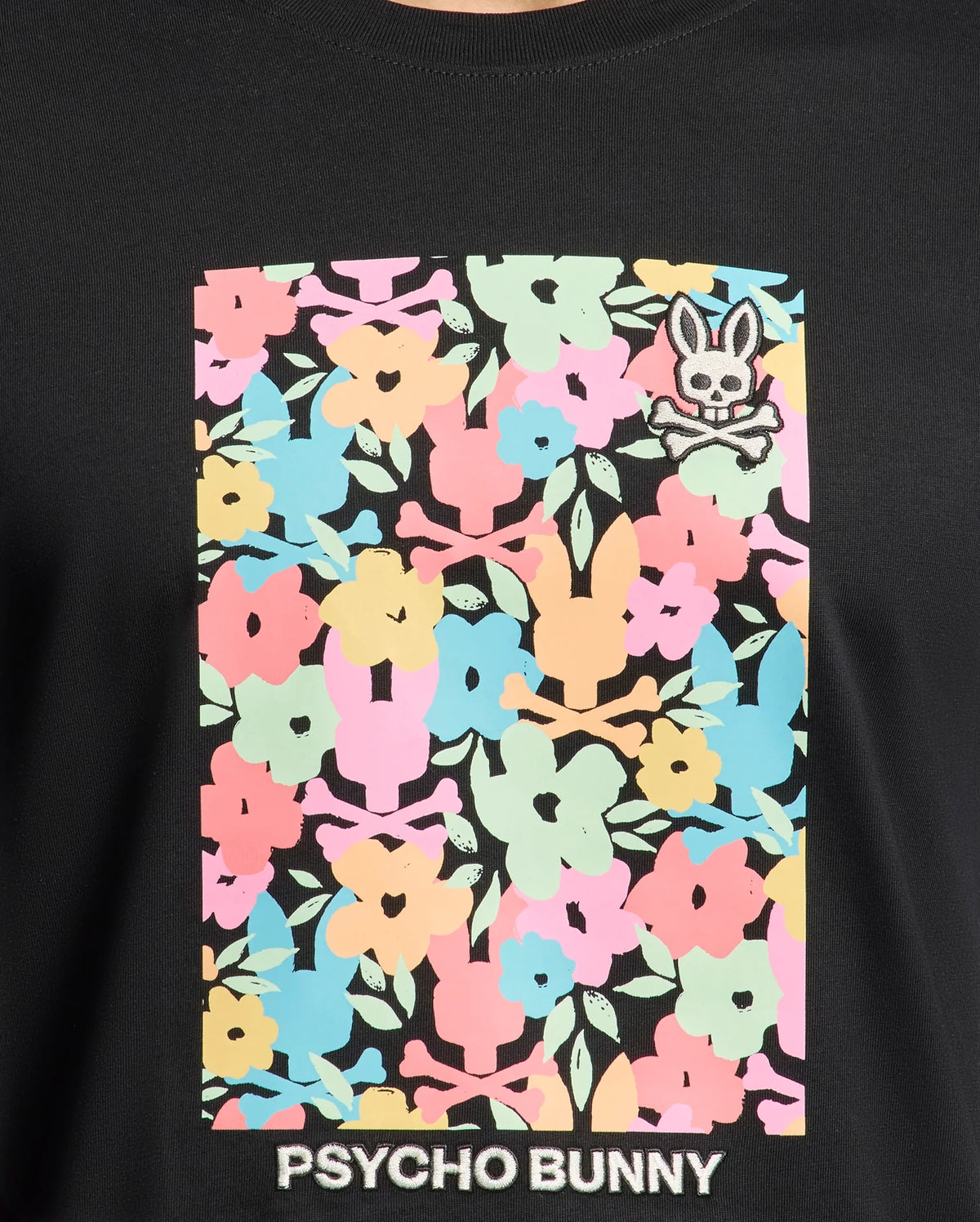 Experience all-day comfort in the Mens Lemmon Graphic Tee by Psycho Bunny, crafted from soft black Pima cotton adorned with colorful pink, blue, yellow, and green floral patterns. A small Bunny graphic with crossbones sits top right, and "Psycho Bunny" is elegantly printed at the bottom.