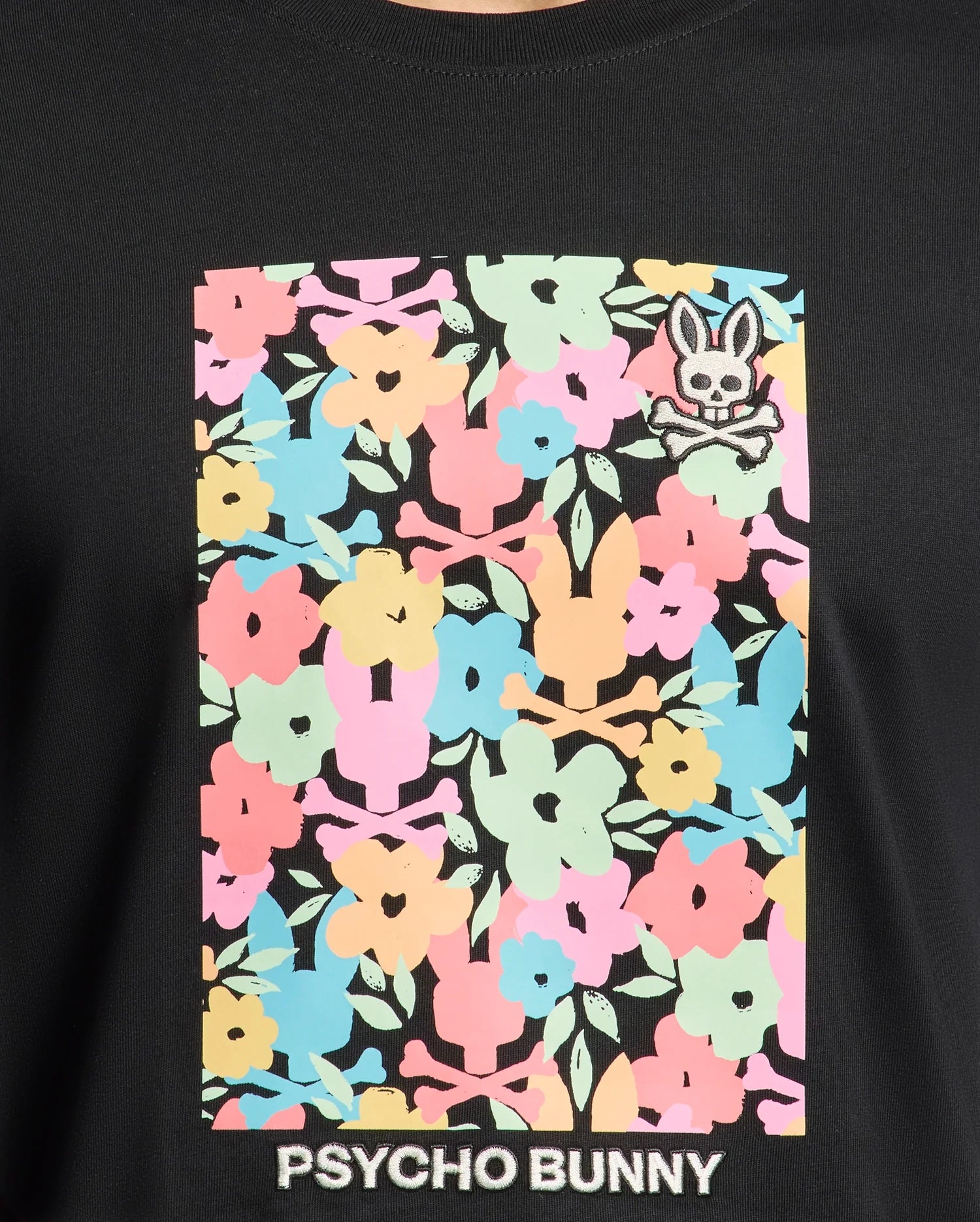 Experience all-day comfort in the Mens Lemmon Graphic Tee by Psycho Bunny, crafted from soft black Pima cotton adorned with colorful pink, blue, yellow, and green floral patterns. A small Bunny graphic with crossbones sits top right, and "Psycho Bunny" is elegantly printed at the bottom.