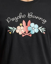 The MENS MEYLON GRAPHIC TEE by Psycho Bunny features soft black Pima cotton with white "Psycho Bunny" text, a playful pink bunny head with crossbones, and colorful pastel flowers in pink, blue, and yellow.