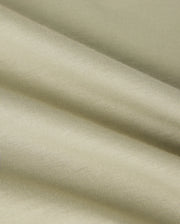 A close-up image of a light beige, textured Pima cotton fabric with visible folds creating soft shadows. The fabric appears smooth with a fine weave, showcasing its subtle sheen and gentle draping, reminiscent of the luxurious quality found in a Psycho Bunny MENS KAYDEN GRAPHIC TEE - B6U676C200.