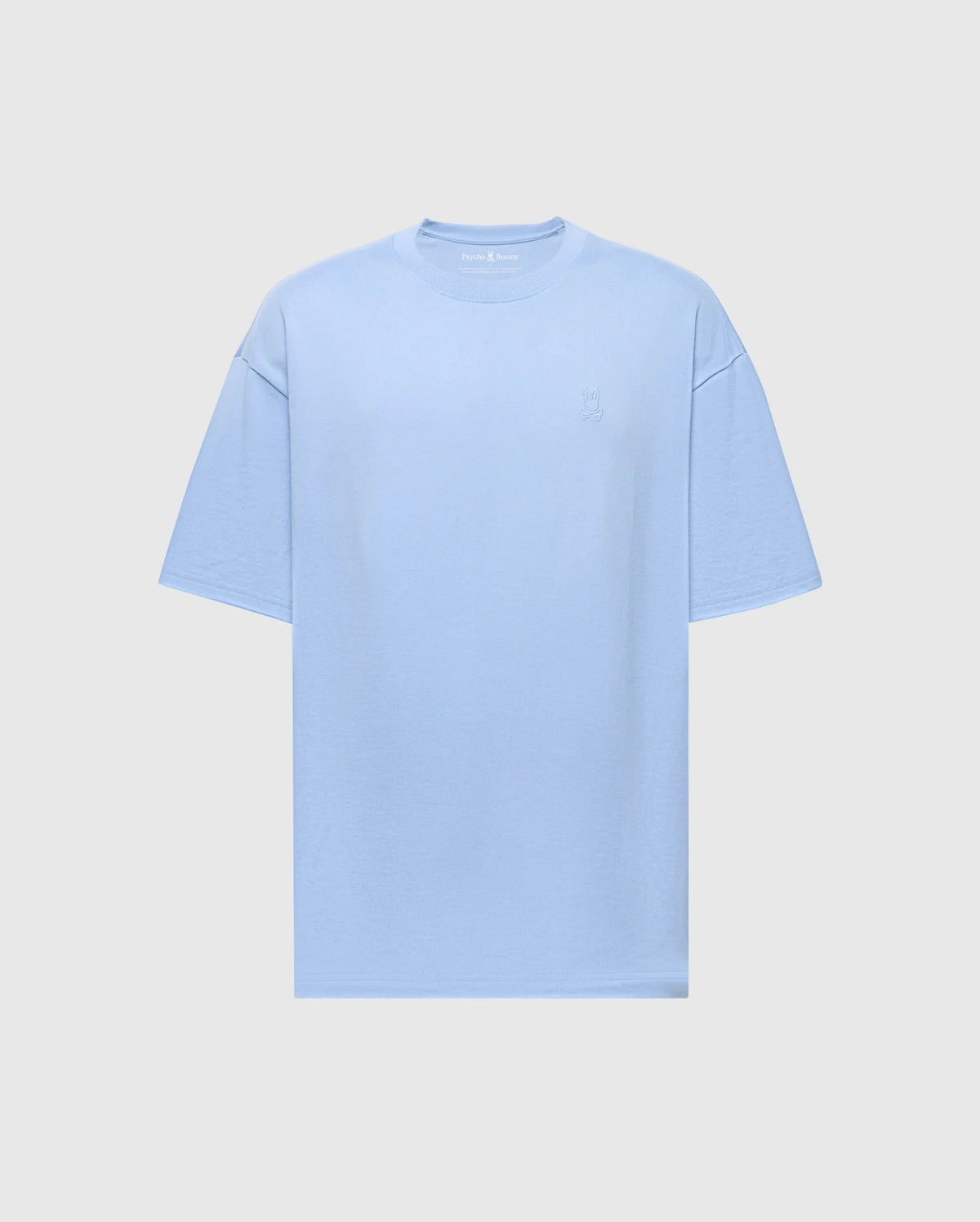 The Psycho Bunny MENS DUKE OVERSIZED TEE (B6U742D200) is a light blue heavyweight jersey T-shirt with a relaxed fit. It features short sleeves and a subtle embroidered design on the left chest, displayed on a plain white background.