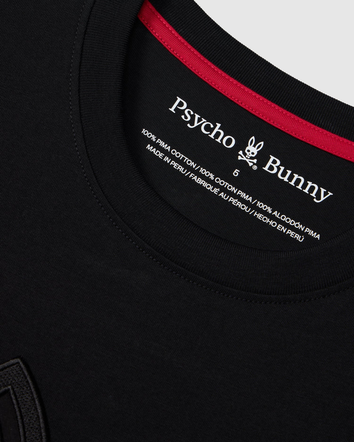 Close-up of the neckline of a Psycho Bunny MENS MALTON GRAPHIC TEE - B6U795D200 in black. The shirt label showcases the brand's logo, fabric details, and country of manufacture. It states "100% Pima Cotton" and "Made in Peru" in multiple languages, with a rabbit logo included.