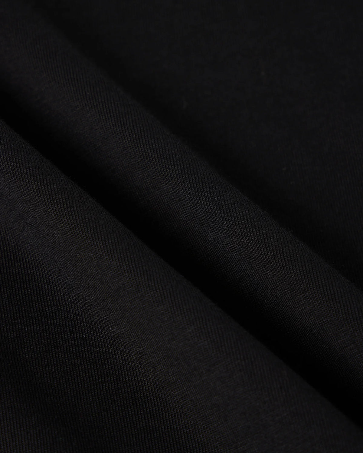 Close-up view of the Psycho Bunny MENS MALTON GRAPHIC TEE - B6U795D200, crafted from black Pima cotton fabric with a smooth texture and subtle diagonal lines. The sleek and sophisticated appearance is enhanced by the slight drape, highlighting its fluidity and softness—a hallmark of garments made in Peru.