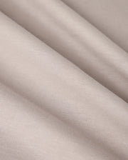 A close-up image of the MENS MALTON GRAPHIC TEE by Psycho Bunny, showcasing light beige fabric with a smooth texture and subtle diagonal folds, reminiscent of the fine weave found in Pima cotton. The material appears soft and finely woven, creating gentle shadows and highlights across its surface.