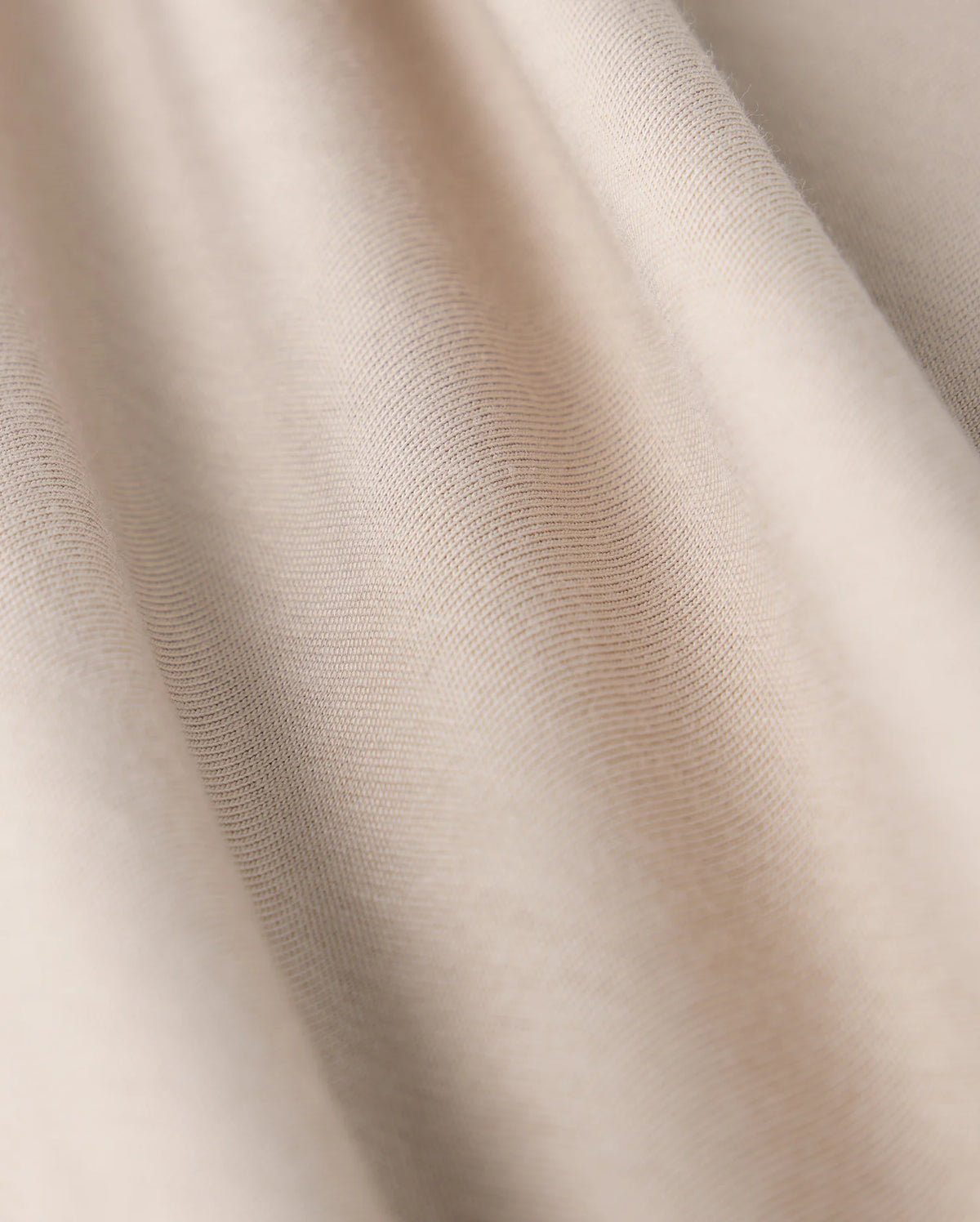 Close-up of the MENS CAMPO POCKET TEE - B6U801D200 by Psycho Bunny, showcasing beige fabric with a smooth texture and gentle folds. This lightweight material, similar to finely woven pima cotton, offers a subtle sheen with soft shadows and highlights.