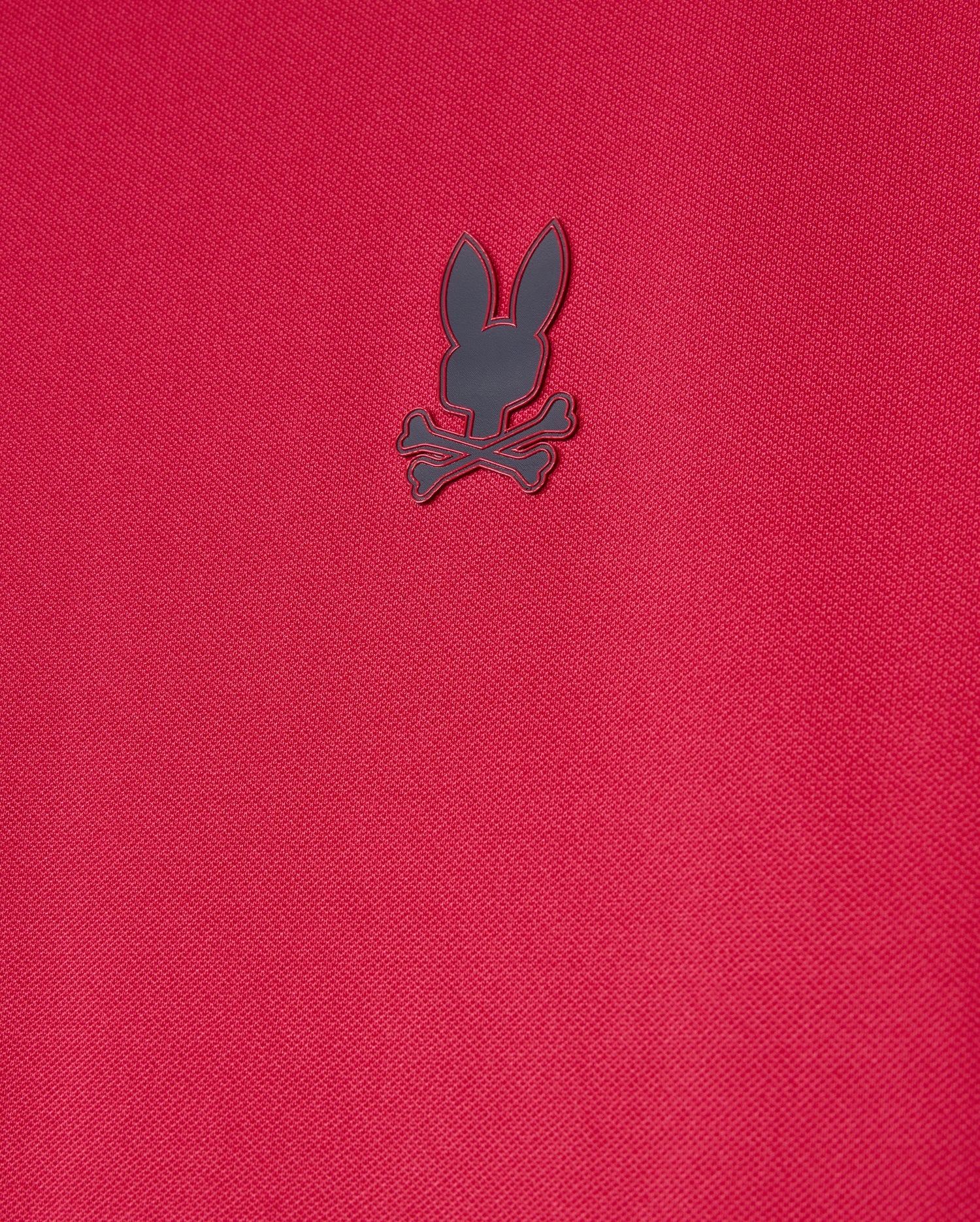 The Psycho Bunny Mens Edmonds Sport Tee (B6U857D200) is a red, textured shirt made from quick-drying, antimicrobial fabric with a small, dark emblem of a rabbit head and crossbones.