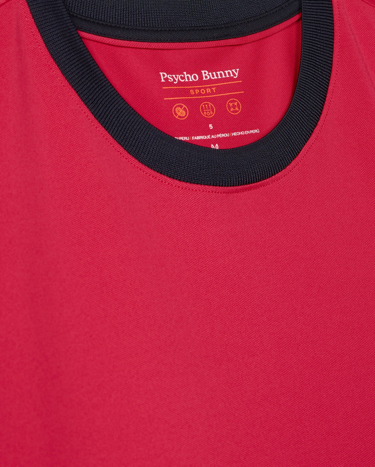 The Psycho Bunny Men's Edmonds Sport Tee (B6U857D200) features a red design with a black collar, crafted from quick-drying antimicrobial fabric. The brand name and care instructions are printed inside near the neckline.