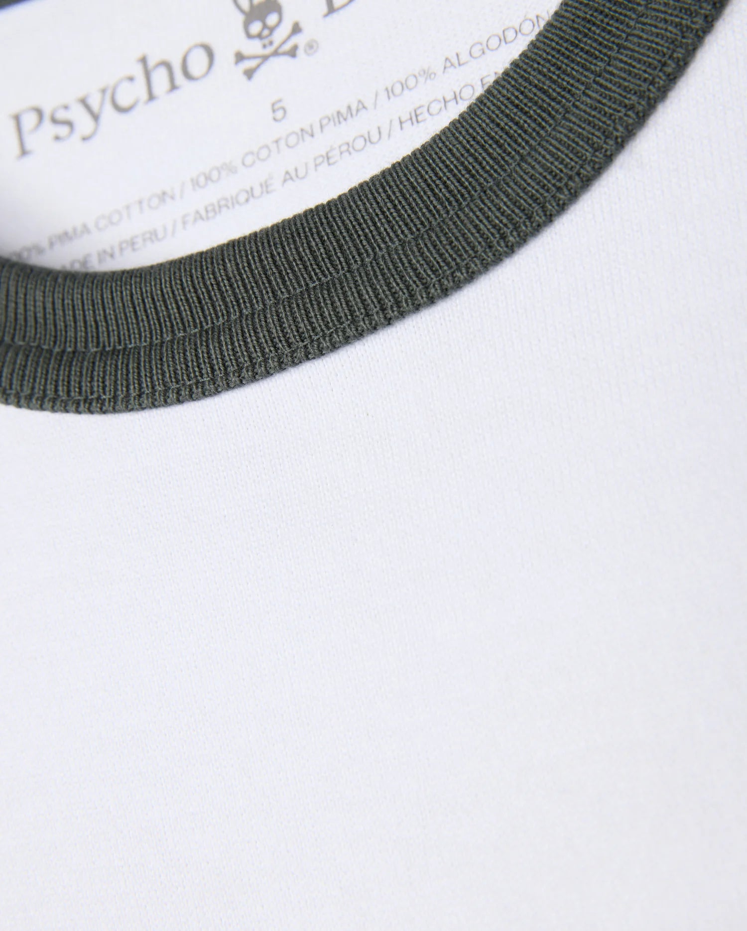 Close-up of a white heavyweight jersey tee featuring a green ribbed collar. The inside label displays the brand name "Psycho Bunny", along with the size and material information, specifying that it is crafted from 100% Pima cotton and produced in Peru. This is part of the MENS LONDON RAGLAN GRAPHIC TEE - B6U896D200 collection.