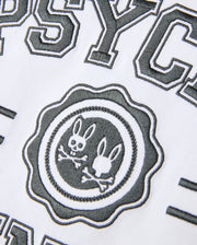 Close-up of a white Psycho Bunny Pima Cotton fabric with black, textured embroidery. This Heavy Weight Mens London Raglan Graphic Tee - B6U896D200 showcases the word "PSYC" above a circular logo featuring two bunny heads and crossbones, accompanied by partially visible surrounding text.