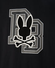 The MENS ZACK GRAPHIC TEE - B6U897D200 by Psycho Bunny features a black graphic tee with a bold letter 'B' outlined in white. Superimposed over the 'B' is a black silhouette of a rabbit head with long ears above two crossed bones, resembling a skull and crossbones motif. This unique design screams Psycho Bunny style.