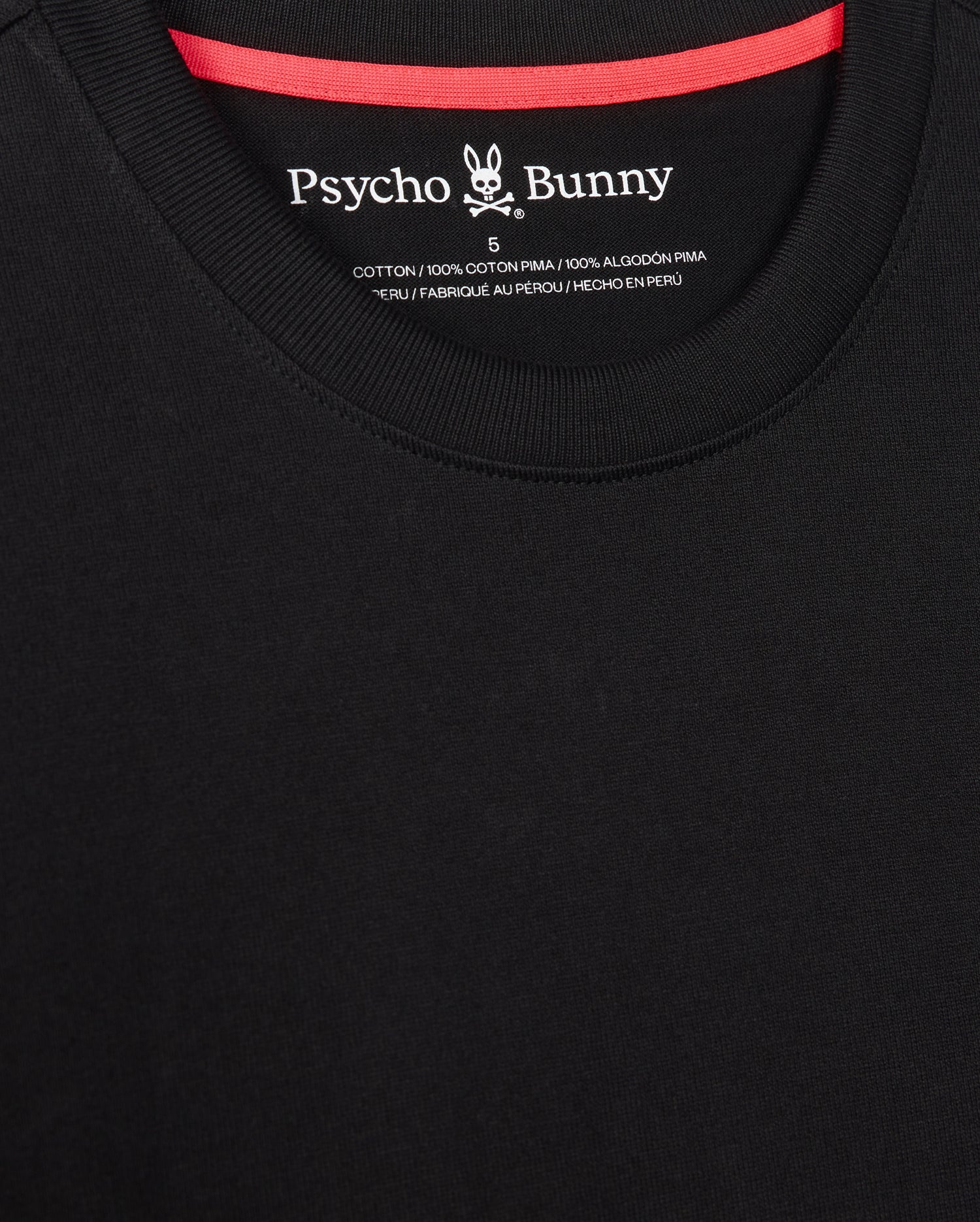 Close-up of a black MENS MONROE HEAVY WEIGHT RELAXED FIT TEE - B6U910D200 with a relaxed fit and red neckline. The logo of Psycho Bunny, featuring a stylized bunny skull and crossbones, is visible inside the collar area. Made of 100% Pima cotton.