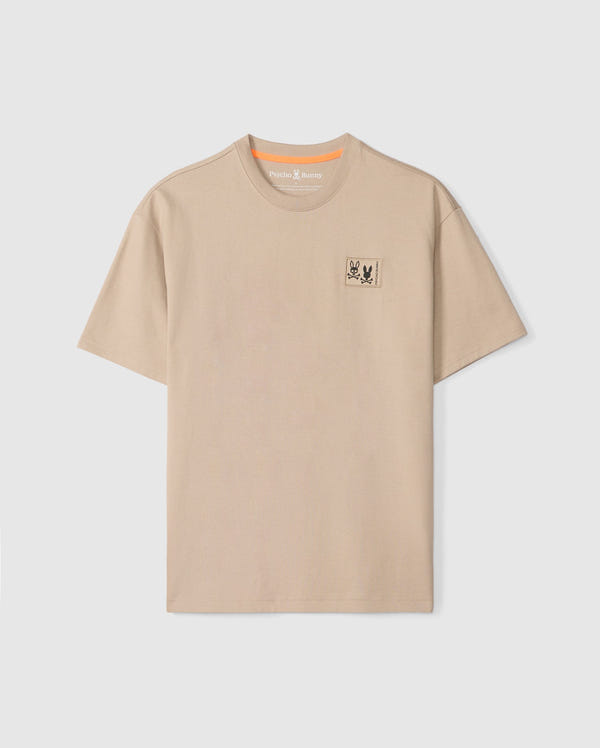 The Psycho Bunny MENS MONROE HEAVY WEIGHT RELAXED FIT TEE - B6U910D200 is a beige Pima cotton tee with a relaxed fit and crew neckline, featuring an embroidered bug emblem on the left chest.