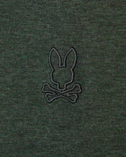 The MENS JAMES PREMIUM CREW NECK TEE - B6U952D200 by Psycho Bunny is made from high-quality Pima cotton and showcases a sophisticated dark green fabric. It features a tonal outline of their signature bunny, embroidered in black above two crossed bones, reminiscent of a skull and crossbones motif.