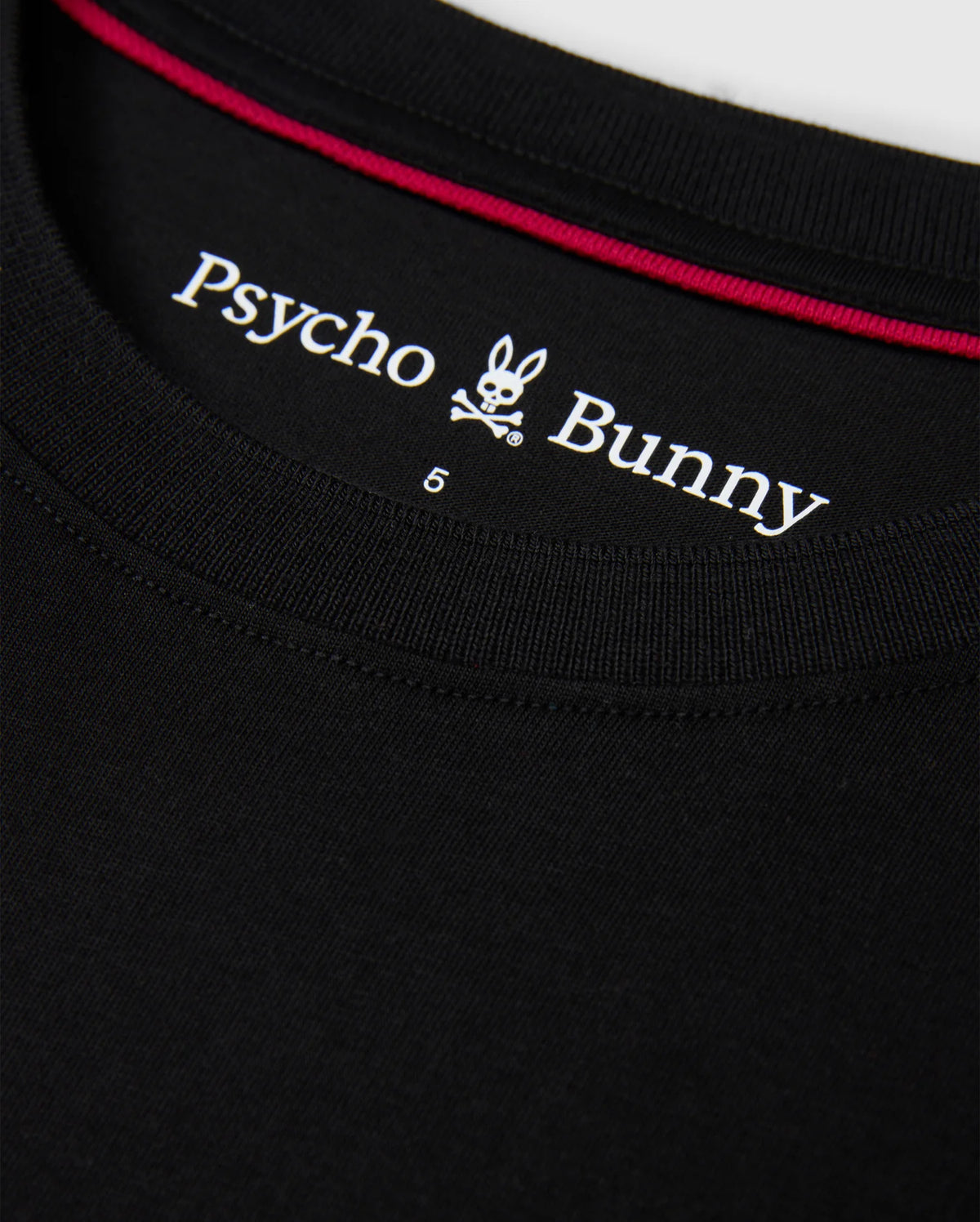 Close-up of the collar of the MENS MALTON FASHION TEE - B6U966D200 in black, showcasing the "Psycho Bunny" logo with its distinctive stylized bunny skull and crossbones, along with a red trim on the inside.