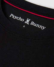 Close-up of the collar of the MENS MALTON FASHION TEE - B6U966D200 in black, showcasing the "Psycho Bunny" logo with its distinctive stylized bunny skull and crossbones, along with a red trim on the inside.