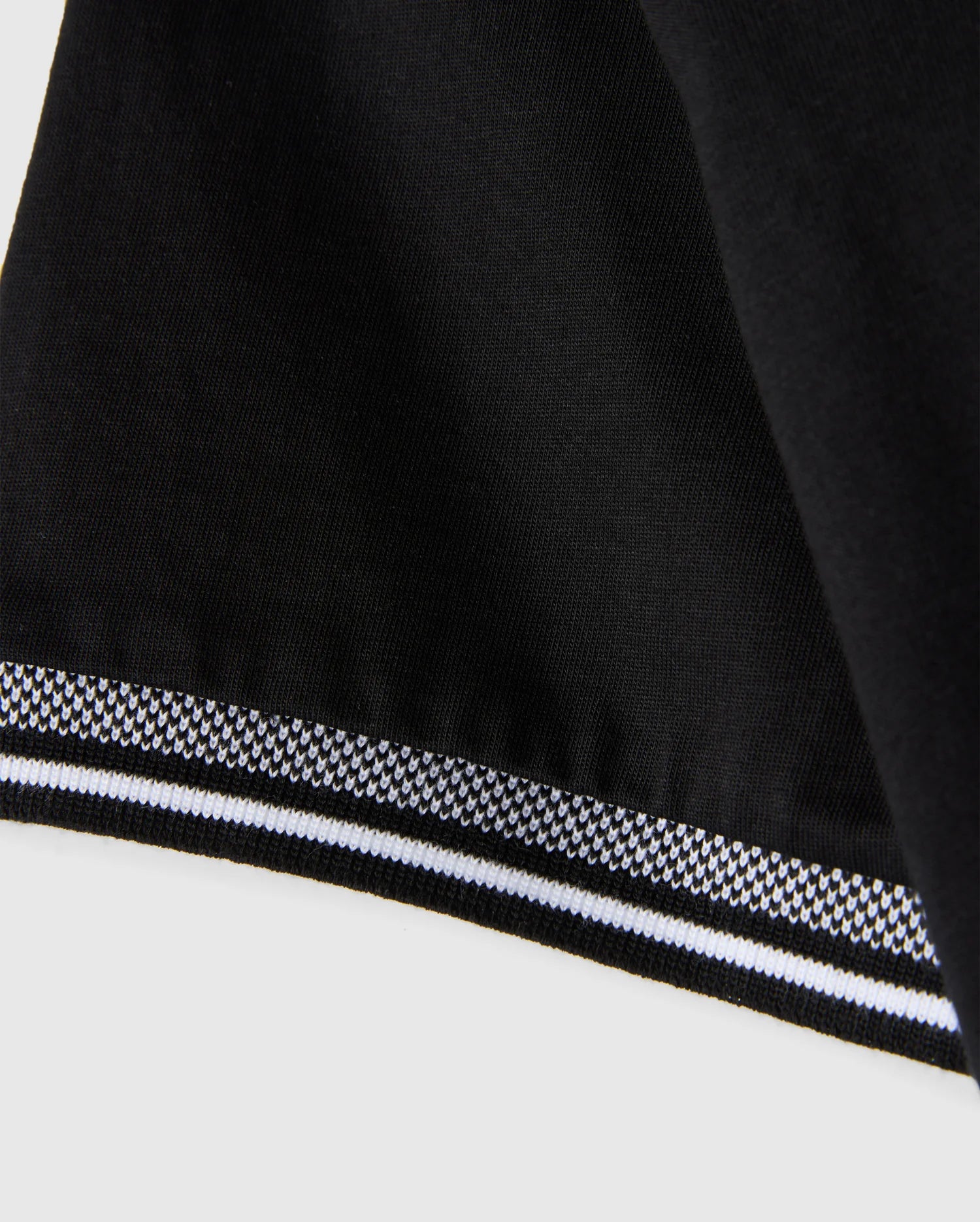 Close-up of a black Men's Malton Fashion Tee by Psycho Bunny, made from pima cotton, featuring a smooth texture and a stylish white and gray striped border at the edge. The border pattern is composed of small geometric shapes, making it an ideal addition to men's fashion tee collections.