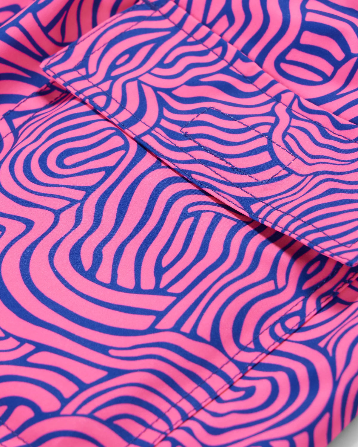 Close-up of fabric with an abstract pattern, ideal for the VERONA PRINT SWIM TRUNK - B6W172B2SW by Psycho Bunny. The background is a bright pink color, and the design consists of wavy, maze-like lines in a bold blue hue. Folds in the quick-dry fabric are visible, adding texture to the image.