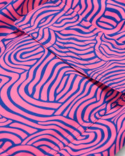 Close-up of fabric with an abstract pattern, ideal for the VERONA PRINT SWIM TRUNK - B6W172B2SW by Psycho Bunny. The background is a bright pink color, and the design consists of wavy, maze-like lines in a bold blue hue. Folds in the quick-dry fabric are visible, adding texture to the image.