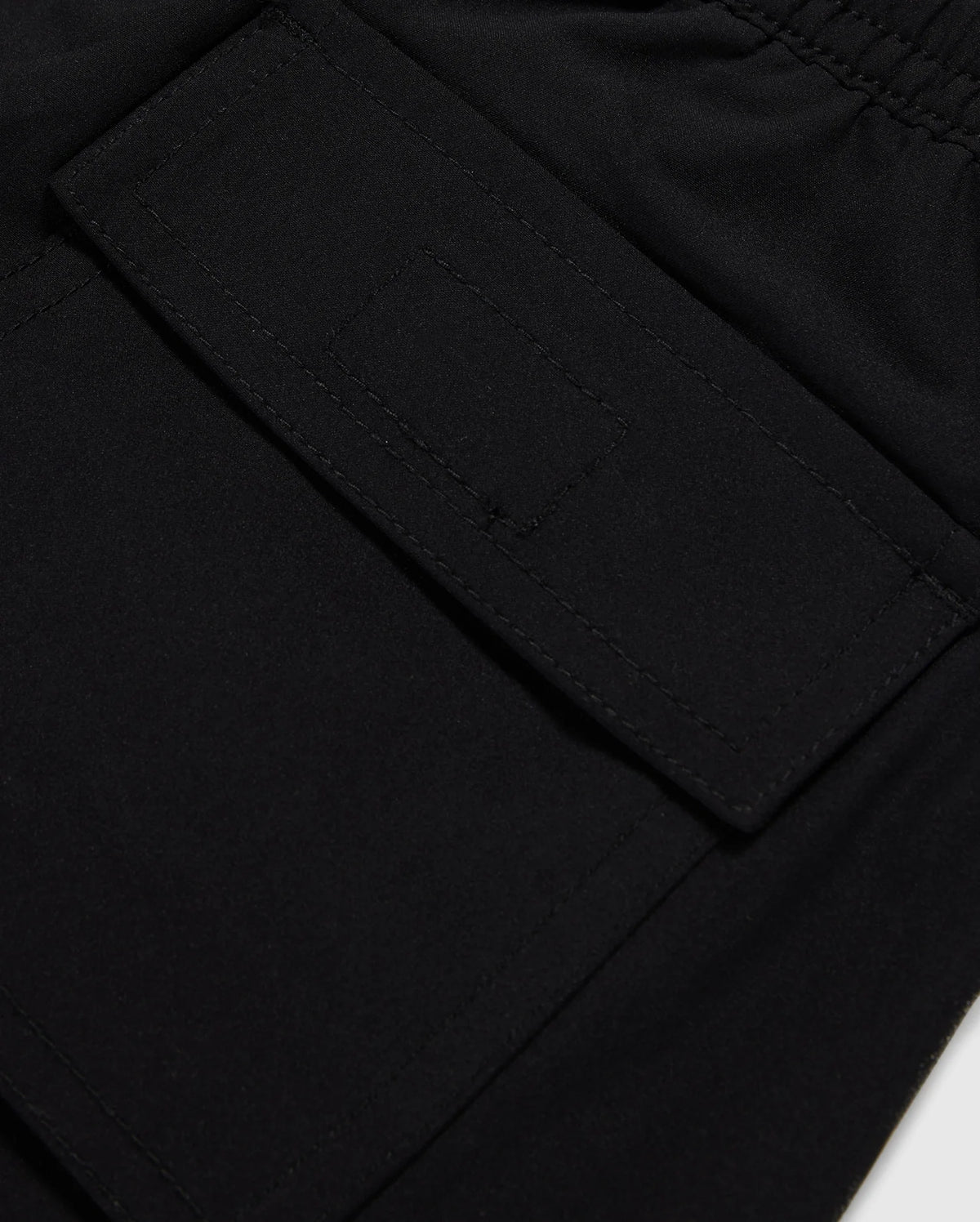 Close-up image of a black fabric texture with a detailed view of a sewn rectangular patch pocket on Psycho Bunny's MENS MALTA HYDROCHROMIC SWIM TRUNK - B6W321B2SW.