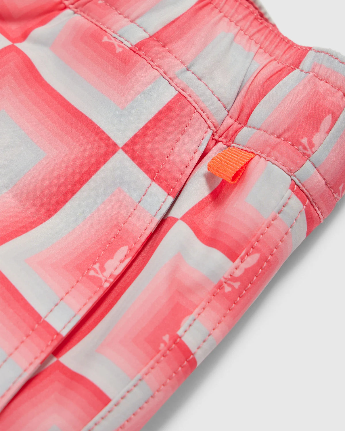 Close-up of a Psycho Bunny MENS UTICA SWIM TRUNK - B6W399B2SW featuring a pink and white all-over print with a visible orange zipper pull.