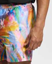 Dressed in Psycho Bunny's MENS MILOS PRINTED SWIM TRUNK - B6W446F200, this person showcases colorful shorts adorned with bunnies and skulls. Ideal for vacation, the quick-dry fabric promises comfort in and out of water.