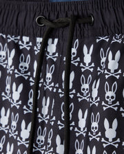 Close-up of the Psycho Bunny MENS TILDEN PRINT SWIM TRUNK - B6W729D200, showcasing a distinctive design where bunny heads replace skulls in a contrasting print. This black garment features white patterns and black drawstrings at the center, made with a quick-dry membrane for optimal performance.
