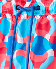 A close-up of Psycho Bunny MENS WALTER LIGHTWEIGHT PRINT SWIM TRUNK - B6W863D200 showcases a lively circular pattern in red, white, and blue. Made from 100% polyester, the trunks feature a blue drawstring threaded through black eyelets, cinched and tied at the front.